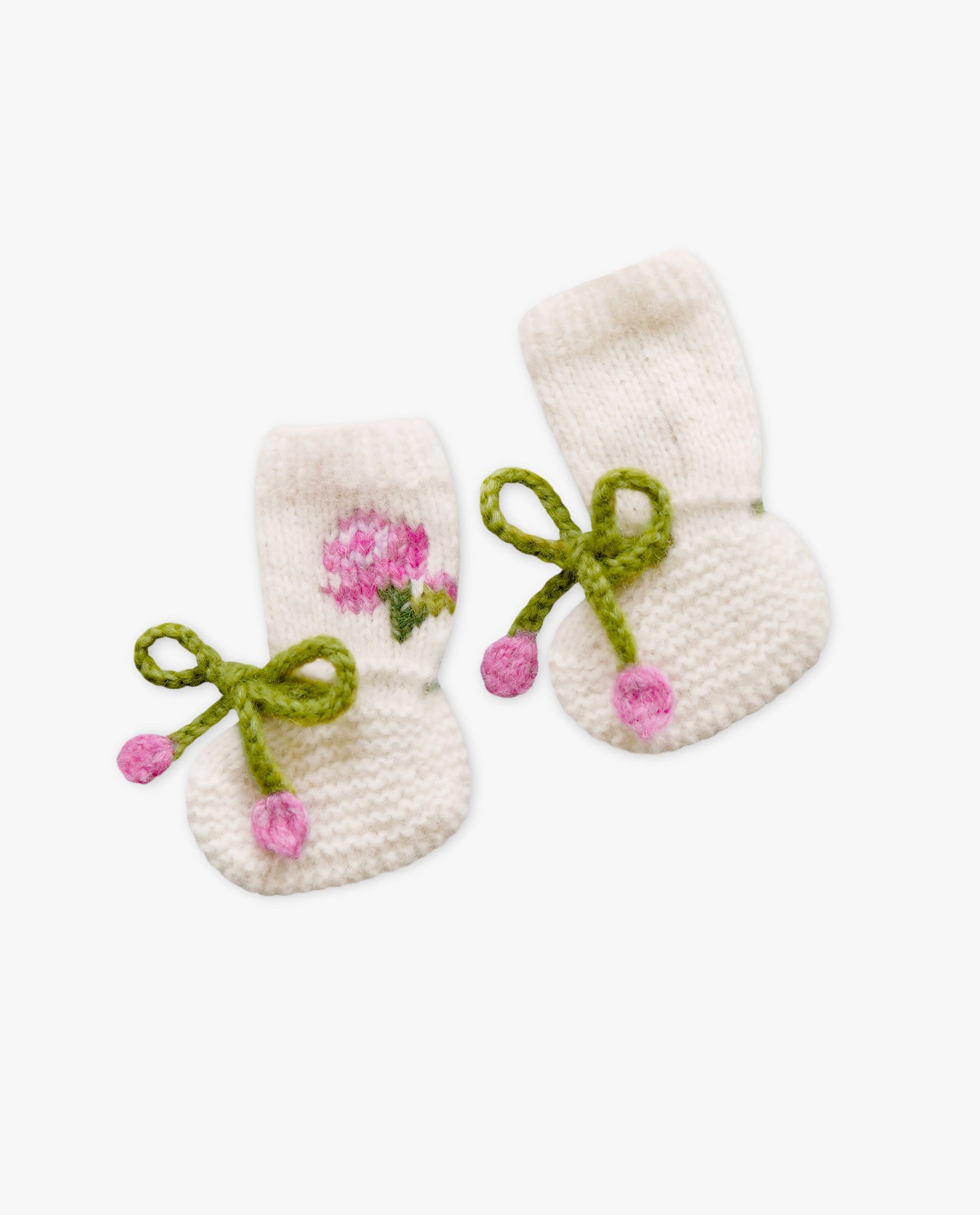 Pair of white baby booties with floral and bow designs on a white background